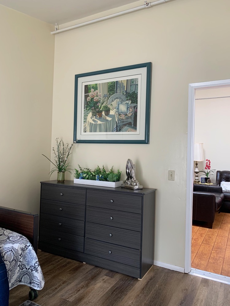 Resident bedroom dresser and framed floral artwork