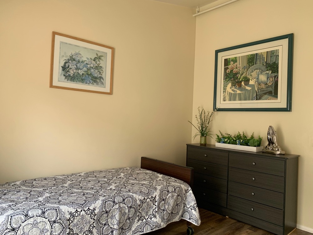 Comfortable single resident bedroom with quilt bedding and wall art