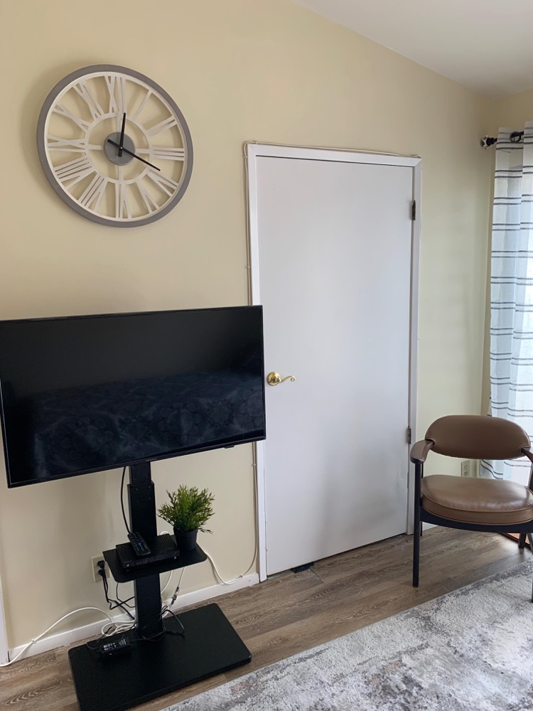 Private bedroom with TV stand, leather chair and large wall clock