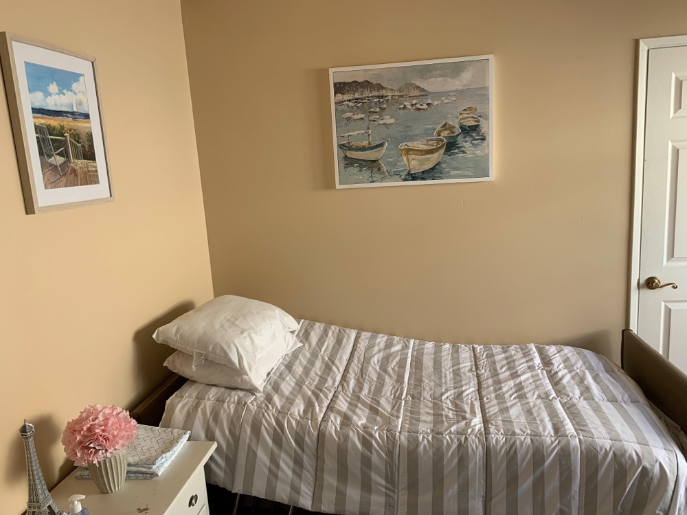 Move-in ready single resident bed with nightstand and beach artwork