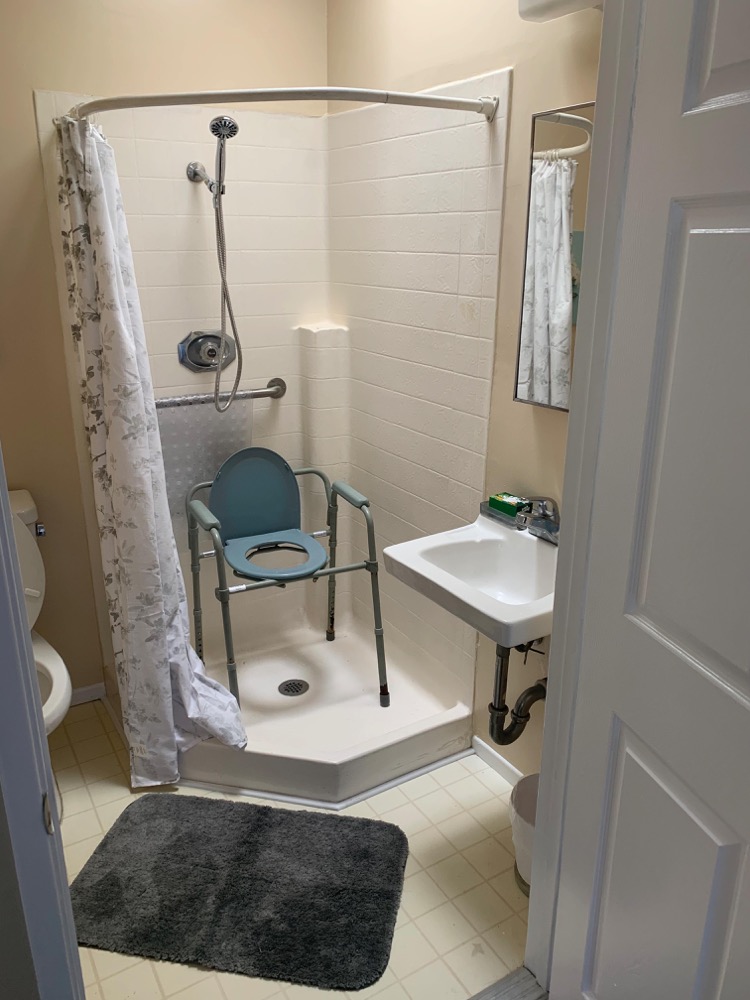 Accessible resident bathroom with walk-in shower and safety grab bars
